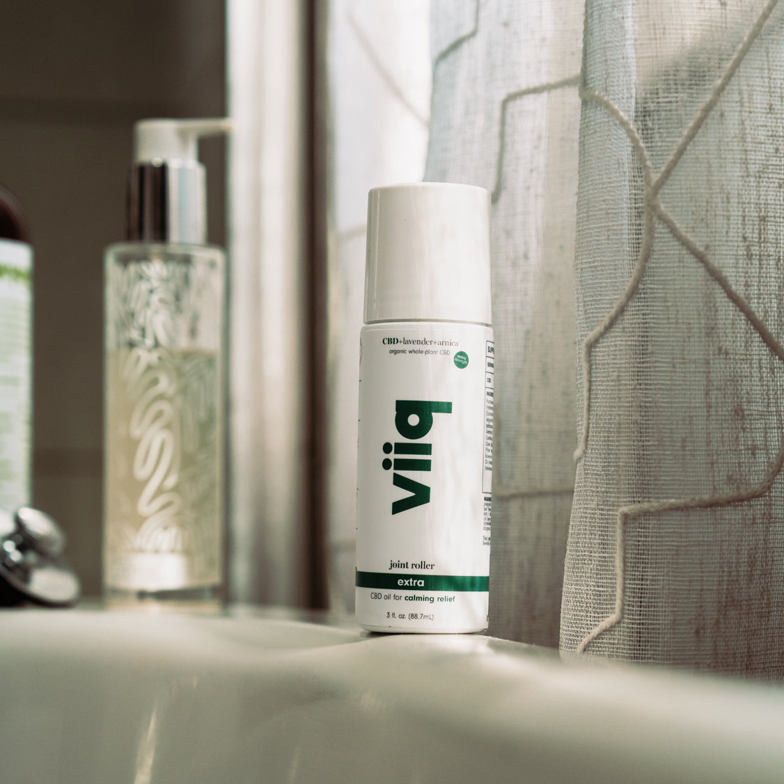 Vliiq joint roller extra product on a bathroom counter with a mirror and shower curtain in the background